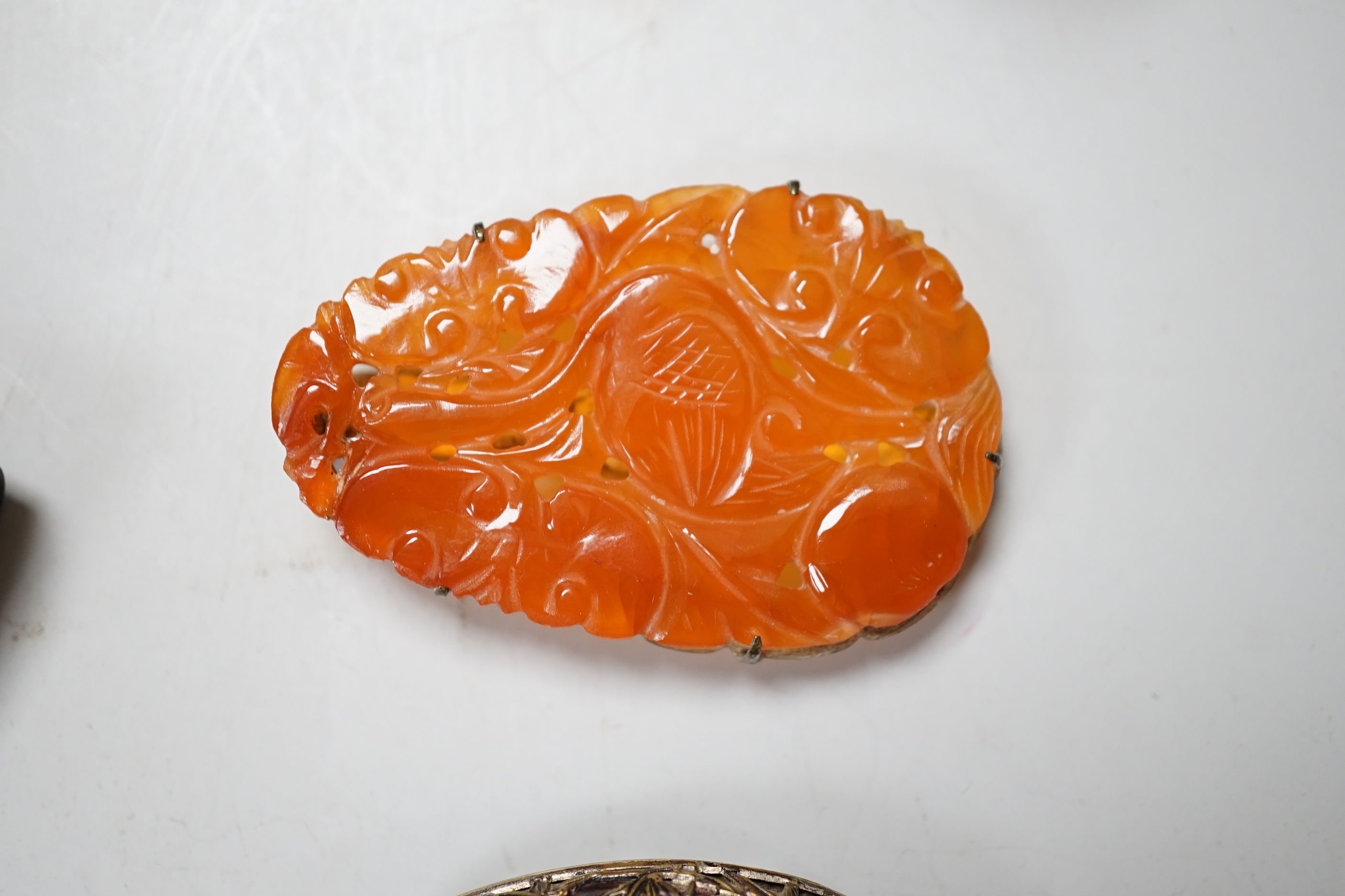 A Chinese chalcedony brooch, a Chinese carved wood brooch, a damascened steel clip and a Japanese trade reference book
